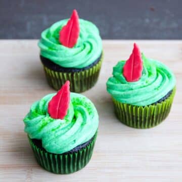 three chocolate cupcakes with buttercream frosting decorated with a peter pan theme