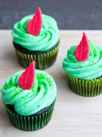 three chocolate cupcakes with buttercream frosting decorated with a peter pan theme