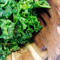 massaged kale salad with nutritional yeast in a wooden bowl