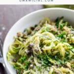 zoodles recipe with lemon caper butter in a white bowl with a fork and green napkin