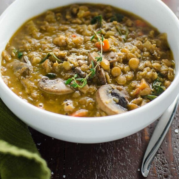 mushroom lentil stew with spinach in a bowl with a spoon and a cloth napkin