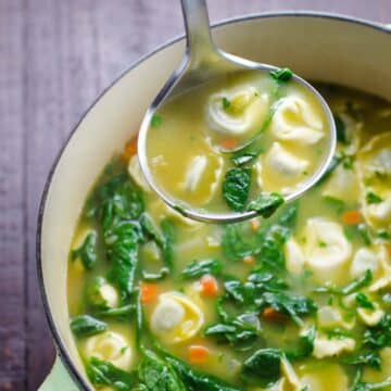 spinach tortellini soup in a pot with a ladle