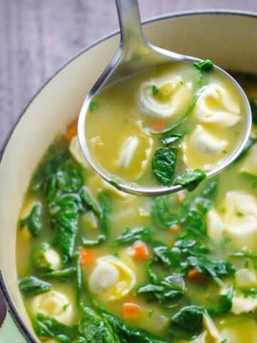 spinach tortellini soup in a pot with a ladle