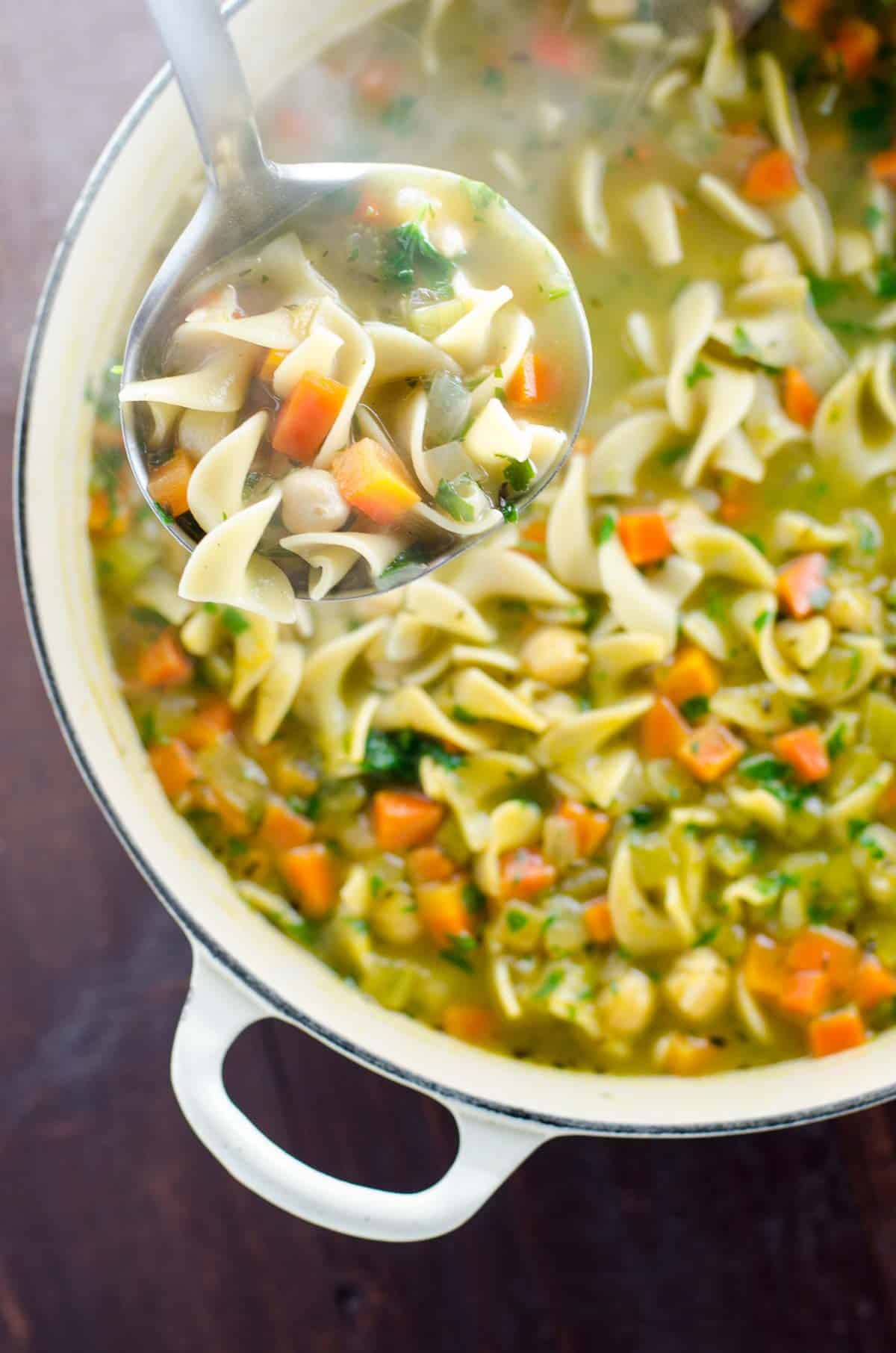 chickpea noodle soup in a pot with a ladle