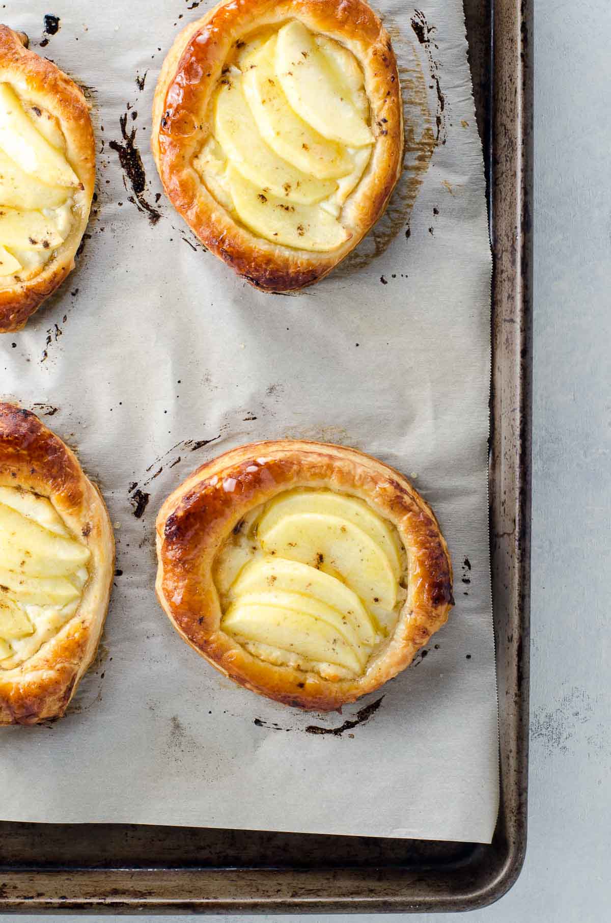 individual puff pastry apple tarts with goat cheese and honey on a baking sheet