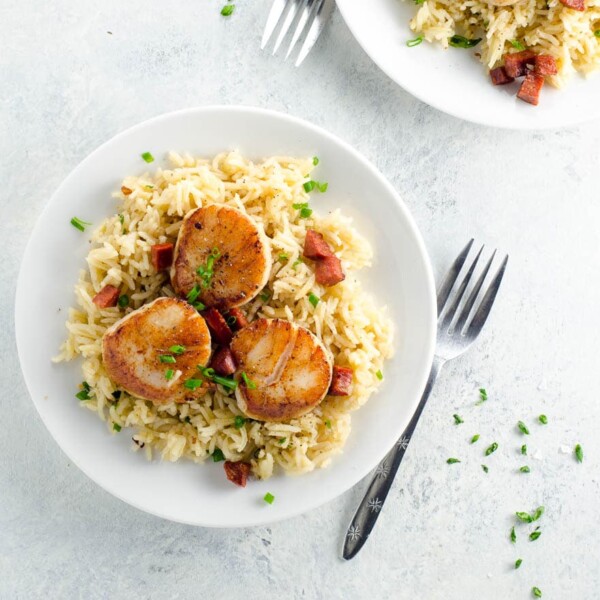 pan seared scallops with chorizo over basmati rice pilaf on plates with forks