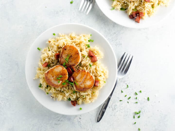 pan seared scallops with chorizo over basmati rice pilaf on plates with forks