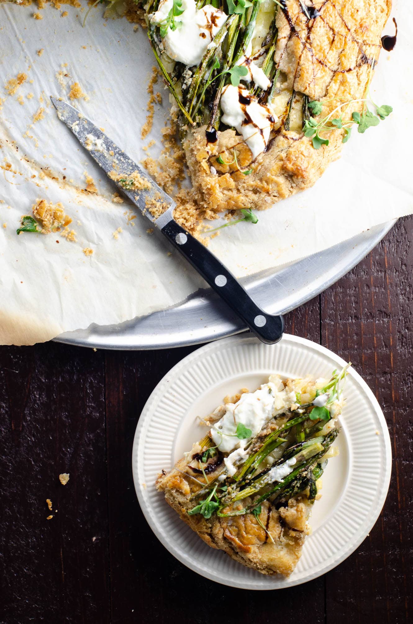 a slice of an asparagus galette with jammy leeks, ricotta, and burrata made with savory tart dough