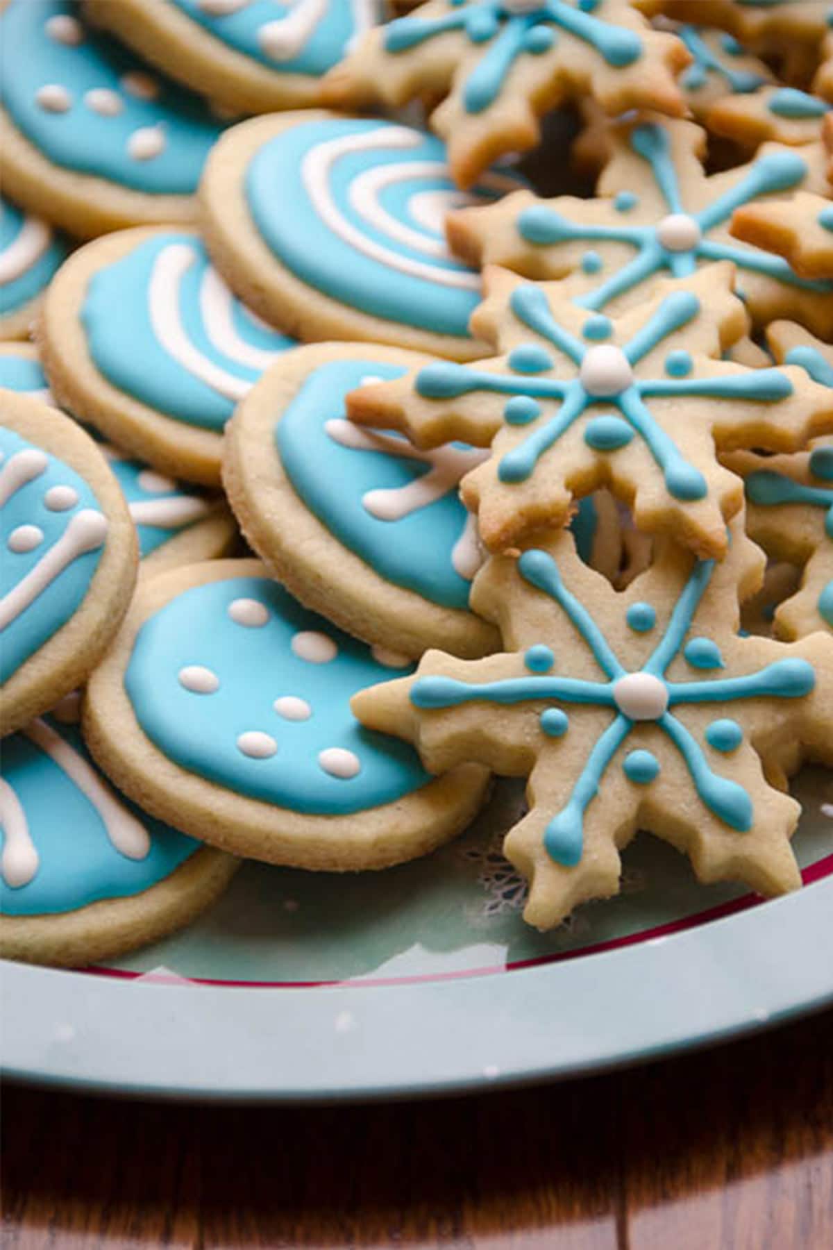a plate of christmas cookies with blue and white biscuiteers royal icing