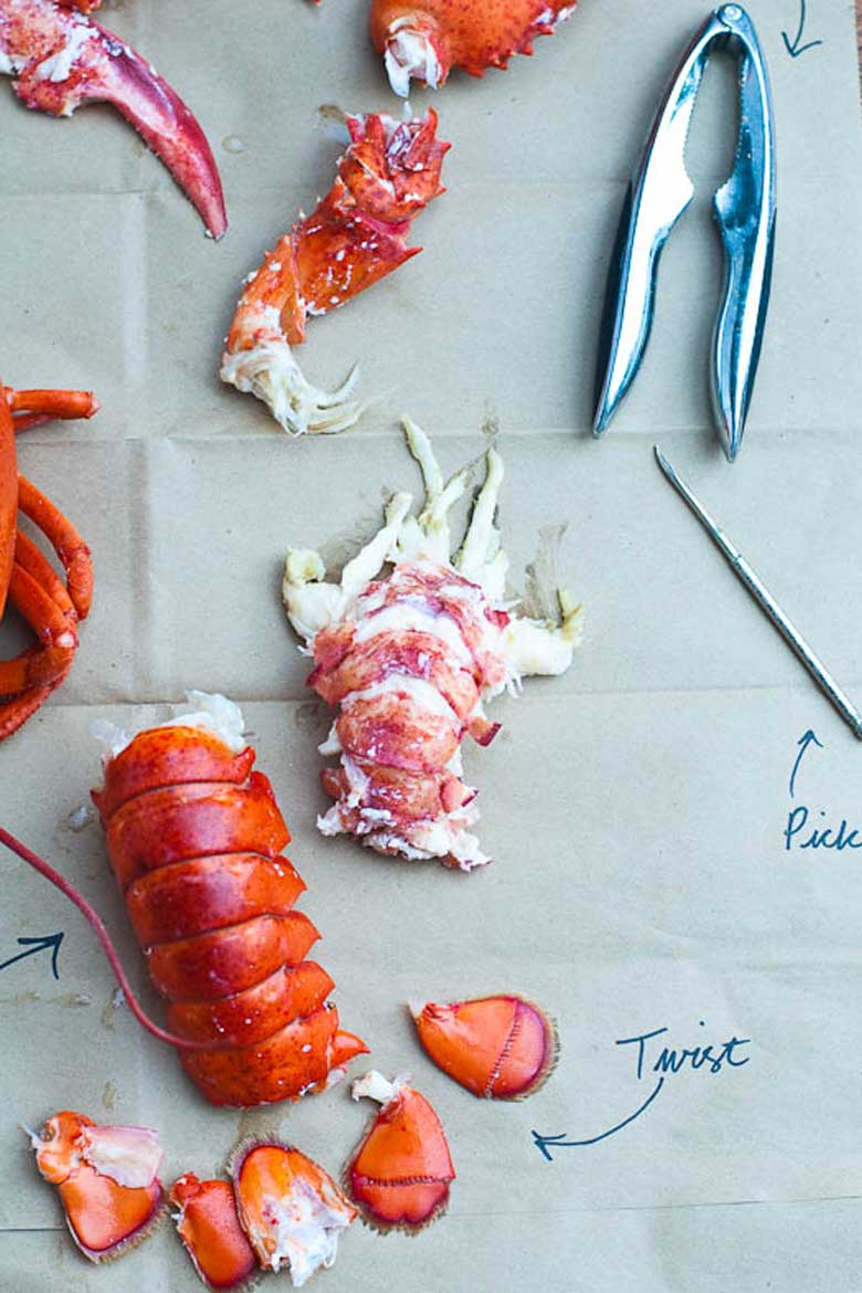 cooking live lobster and how to eat a whole lobster — pieces of lobster on a paper bag, with lobster crackers and a pick