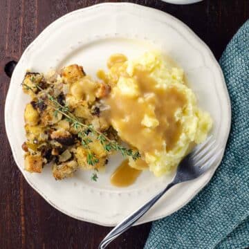 a plate with stuffing, gravy, and old fashioned mashed potatoes for a crowd