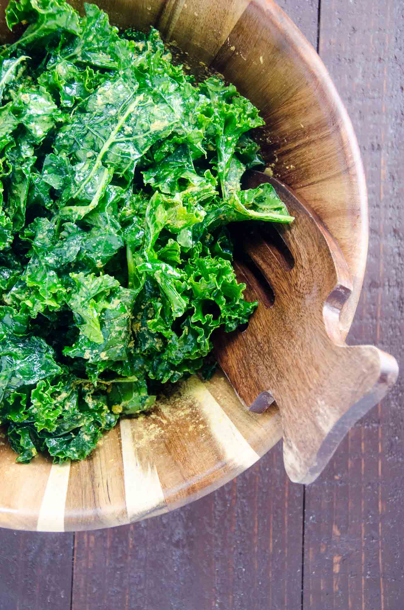 massaged kale salad with nutritional yeast in a wooden bowl