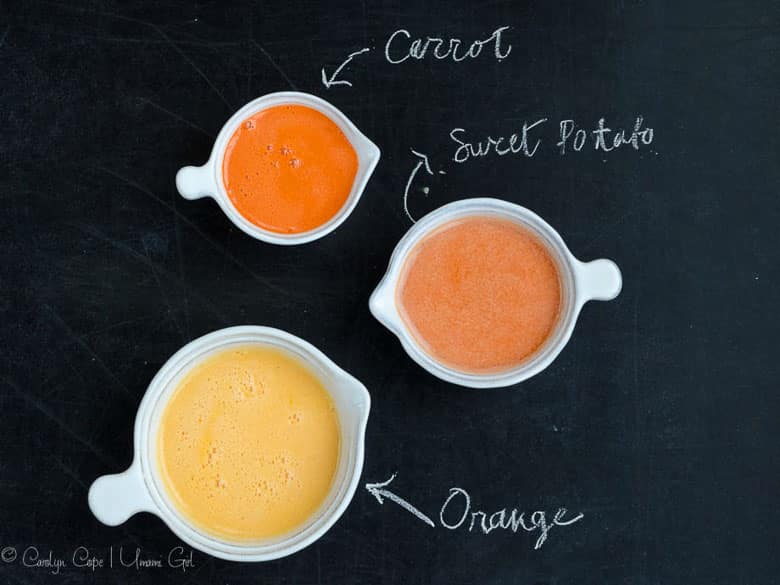 small pitchers with carrot juice, sweet potato juice, and orange juice on a chalkboard background