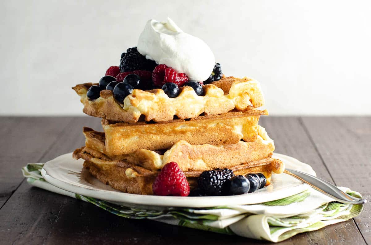 classic vanilla waffles with berries and whipped cream on a plate with a fork