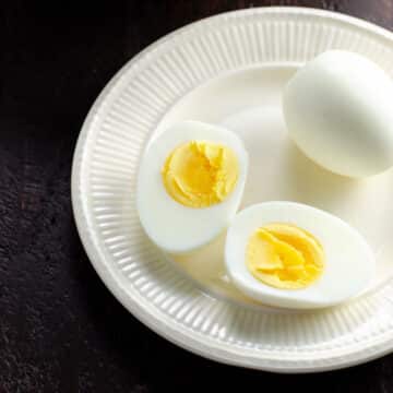 a small plate with two peeled hard boiled eggs, one cut in half