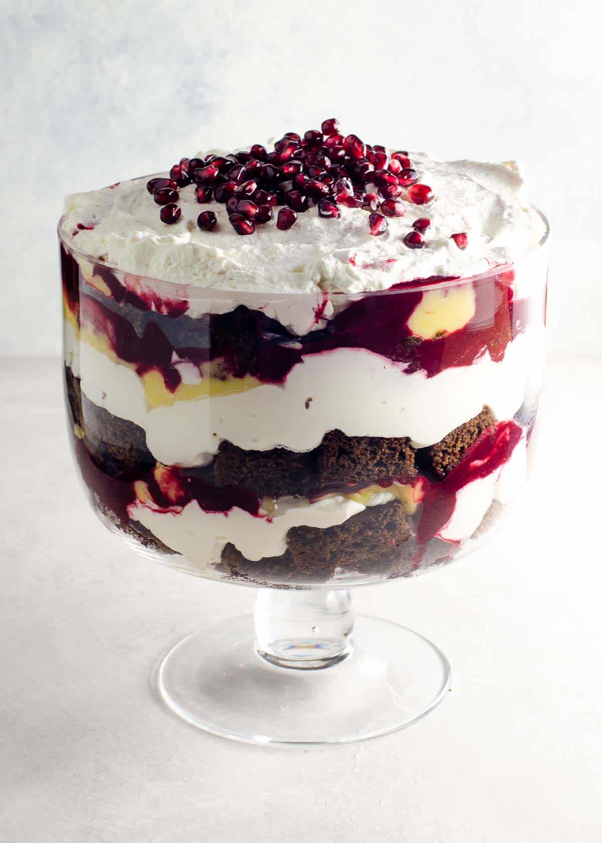 gingerbread trifle with lemon curd, blackberry sauce, and whipped cream in a trifle bowl