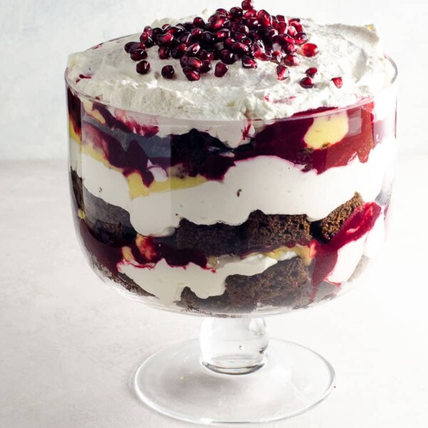 gingerbread trifle with lemon curd, blackberry sauce, and whipped cream in a trifle bowl