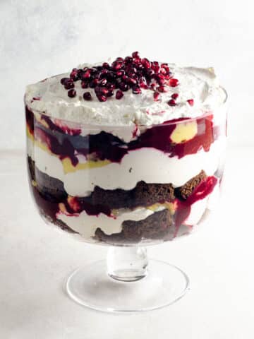 gingerbread trifle with lemon curd, blackberry sauce, and whipped cream in a trifle bowl