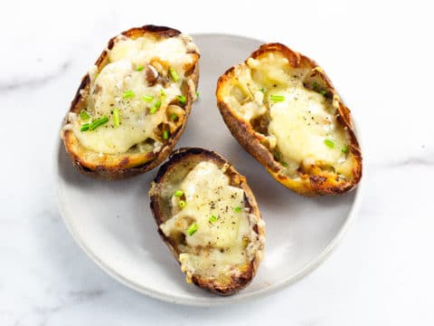 three french onion soup potato skins on a small gray plate on a marble background