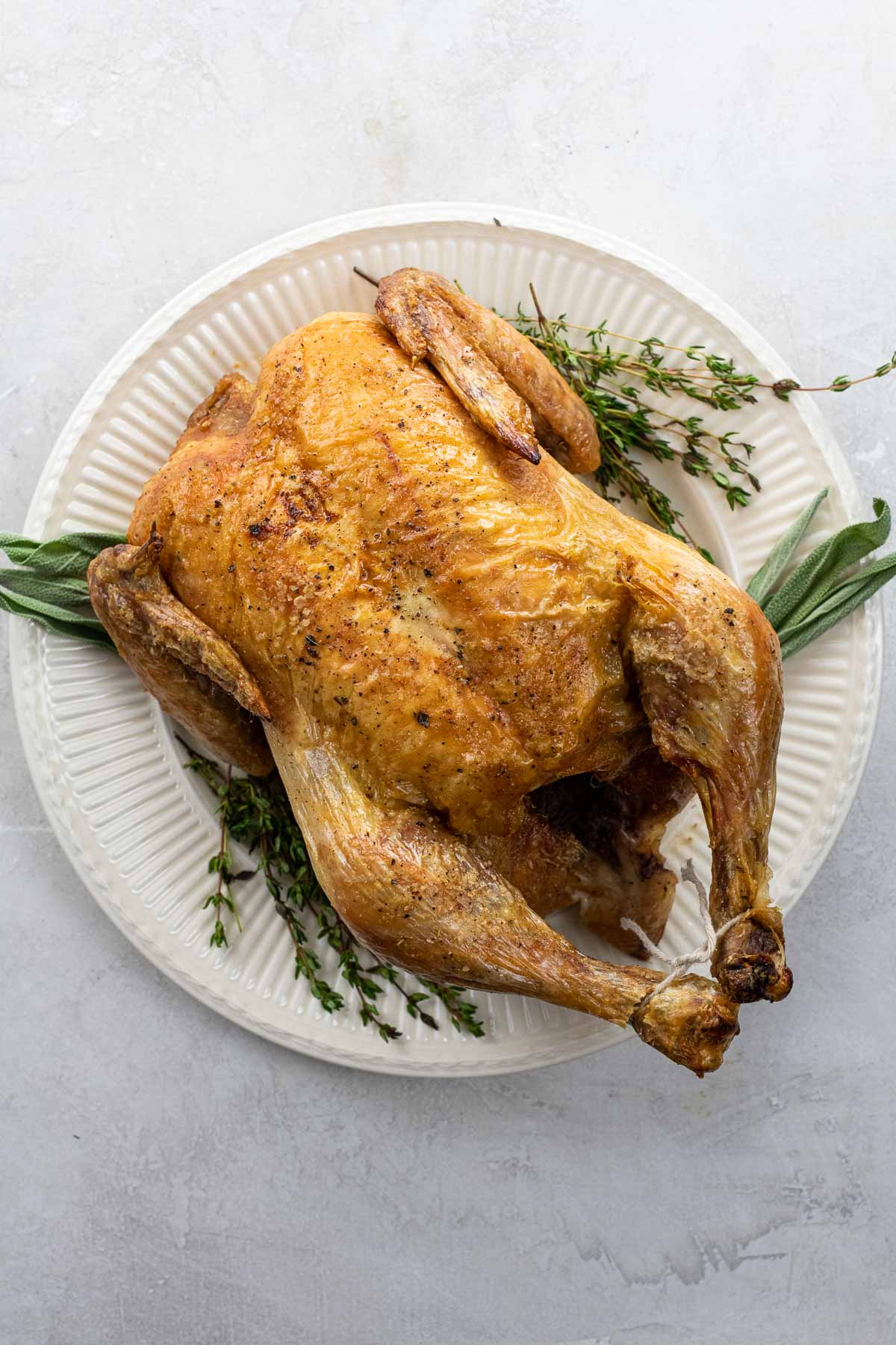 old fashioned roast chicken on a platter with thyme and sage