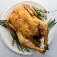 simple roast chicken on a platter with thyme and sage
