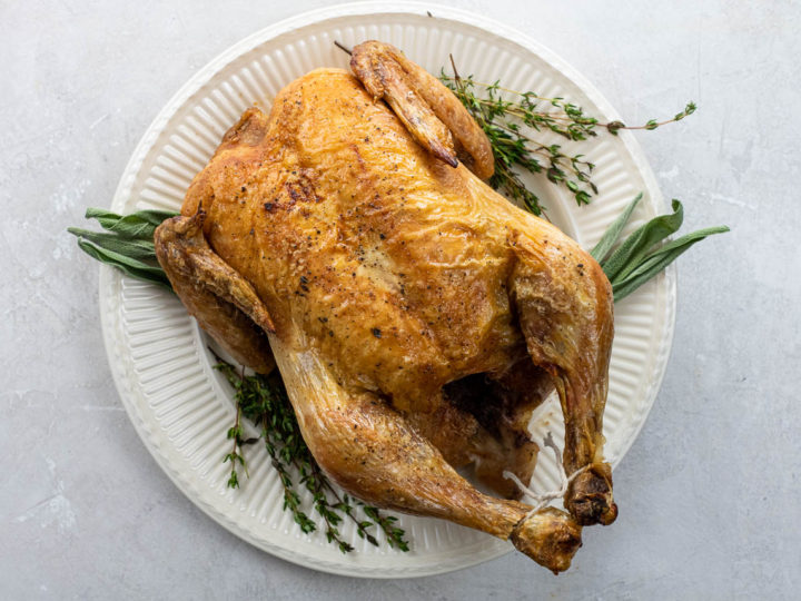 simple roast chicken on a platter with thyme and sage