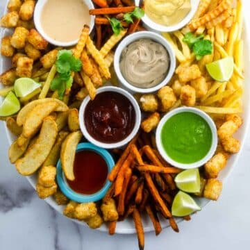 many types of french fries and sauces on a large platter
