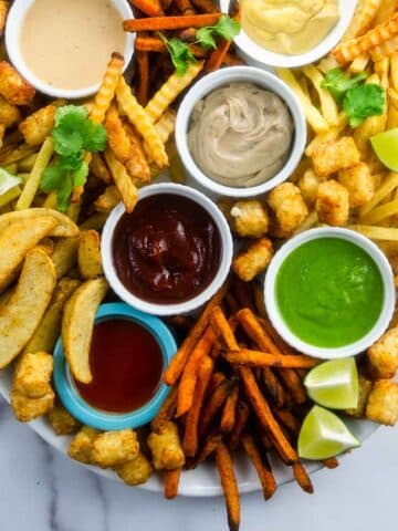 many types of french fries and sauces on a large platter