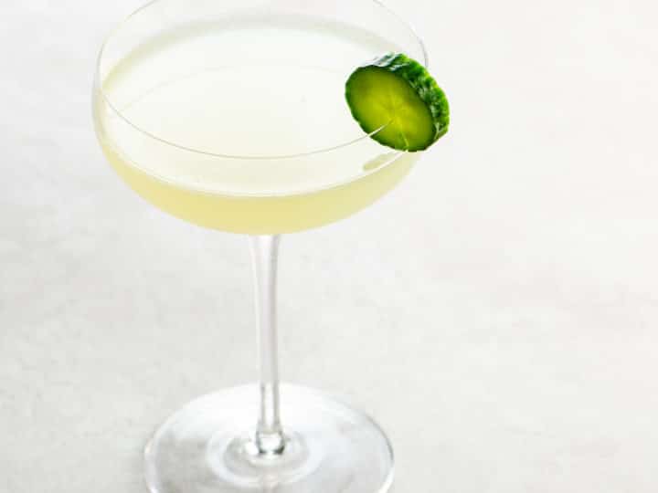 gin gimlet in a coupe glass with cucumber slice garnish on a white background