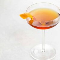 Martinez cocktail recipe with gin, luxardo, and sweet vermouth in a coupe glass garnished with an orange twist