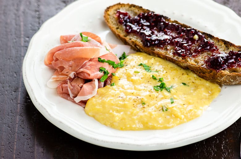 french scrambled eggs on a plate with prosciutto and toast