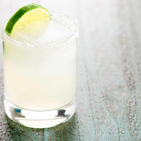 margarita on the rocks in a glass with a salt rim and a lime wheel