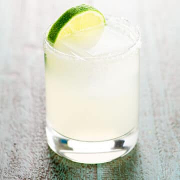 margarita on the rocks in a glass with a salt rim and a lime wheel