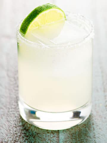 margarita on the rocks in a glass with a salt rim and a lime wheel