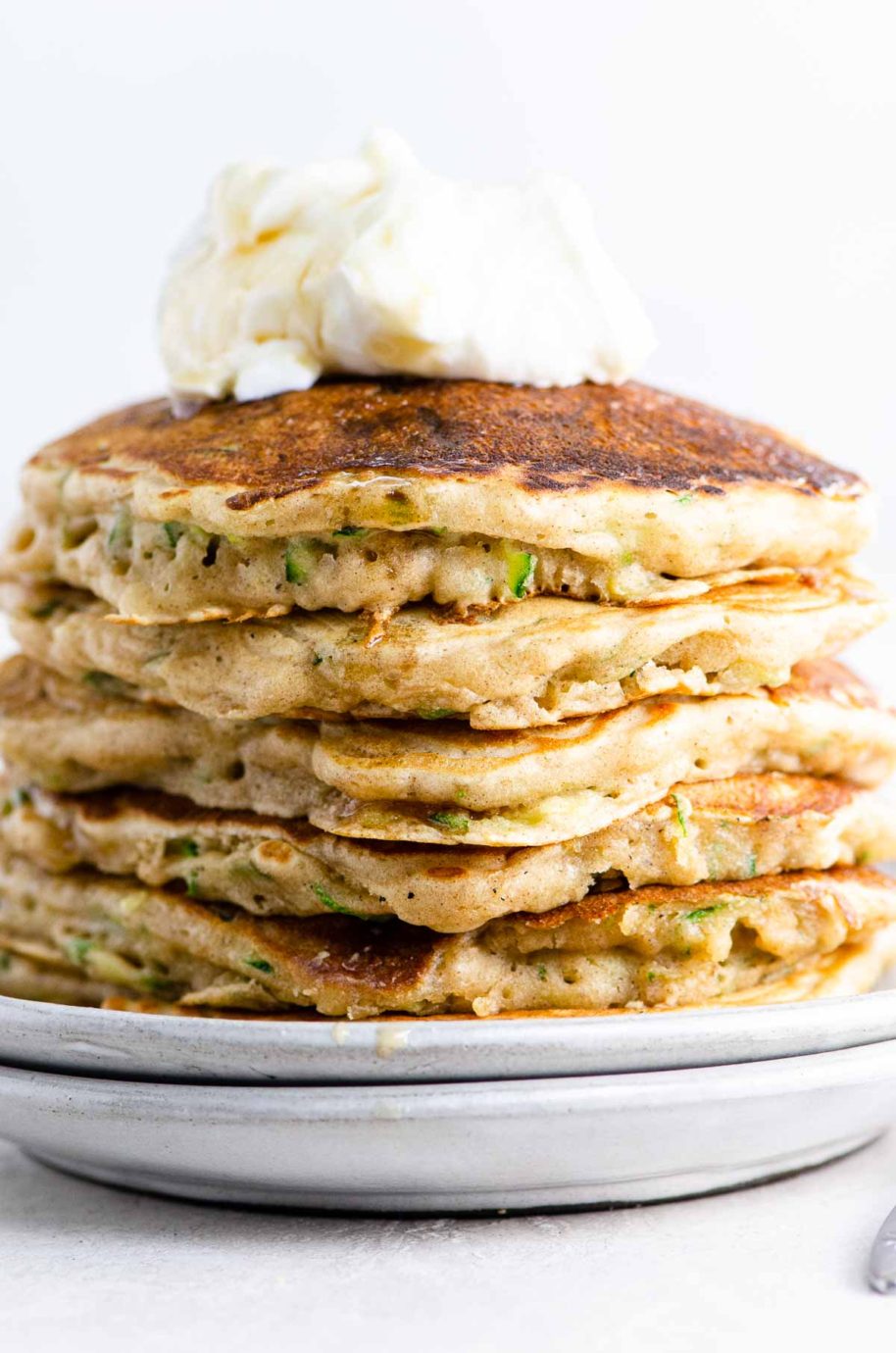zucchini bread pancakes topped with vanilla yogurt and maple syrup