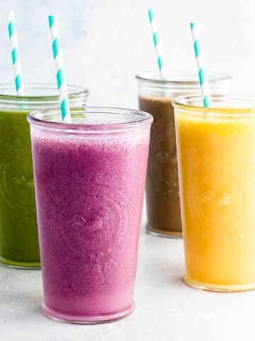 four smoothiebox smoothies in glasses wtih blue and white paper straws