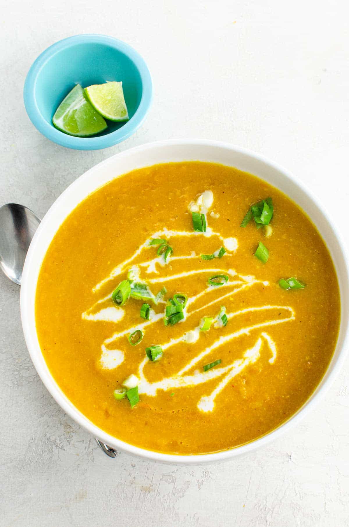 carrot and lentil soup in a bowl with lime wedges