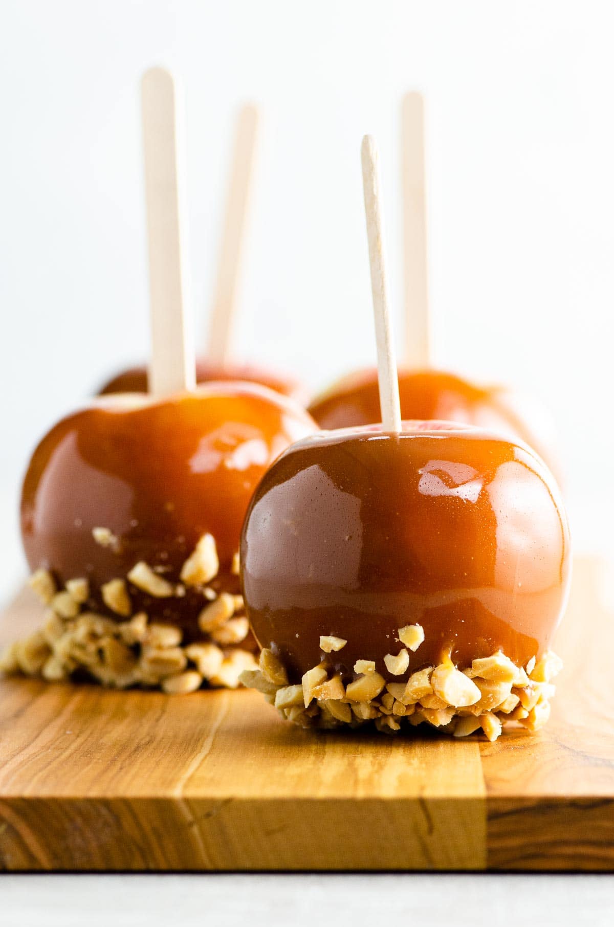 homemade caramel apples with peanuts on a wooden board