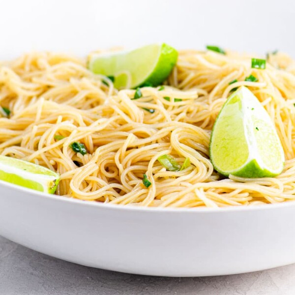 Noodles and a lime wedge on a white plate