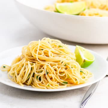Noodles and a lime wedge on a white plate
