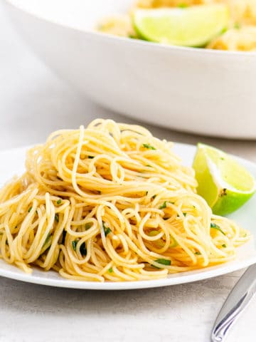 Noodles and a lime wedge on a white plate