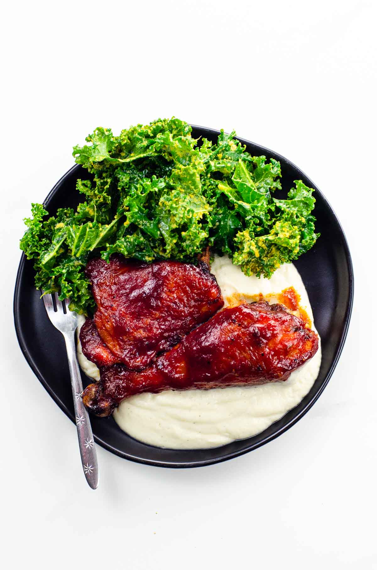 Baked BBQ Chicken Thighs and Legs on a plate with salad and cauliflower puree