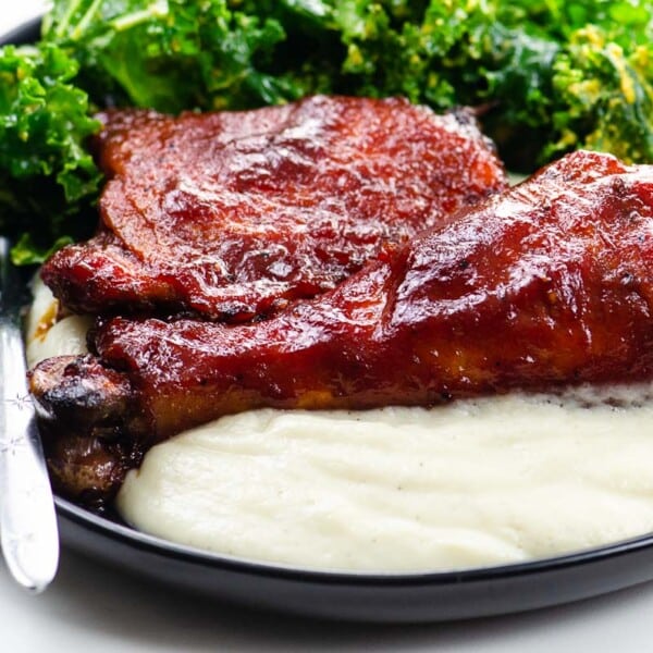 Baked BBQ Chicken Thighs and Legs on a plate with salad and cauliflower puree