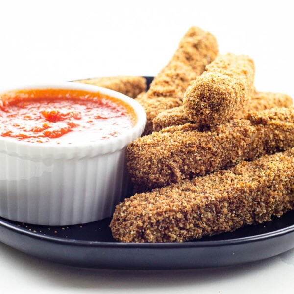 homemade mozzarella sticks and marinara sauce on a black plate