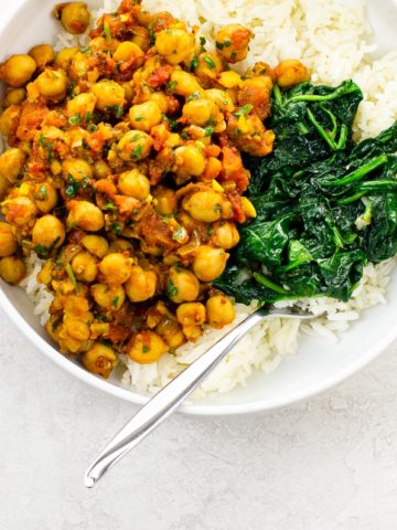 Vegan Chickpea Curry (Chana Masala) in a white bowl with spinach and rice