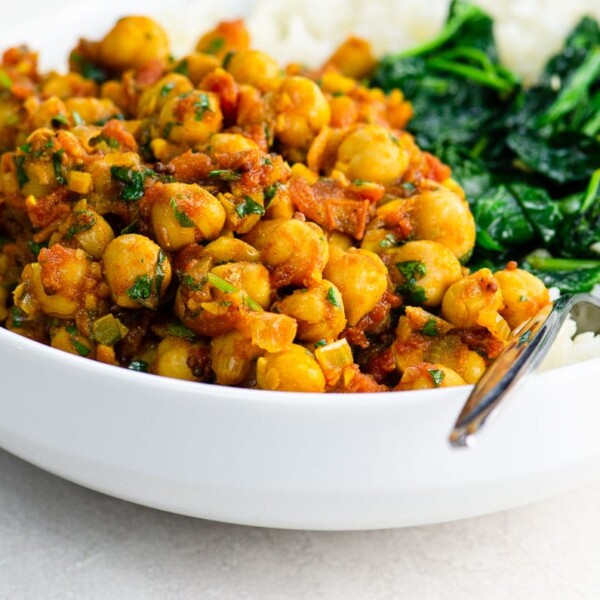 Vegan Chickpea Curry (Chana Masala) in a white bowl with spinach and rice