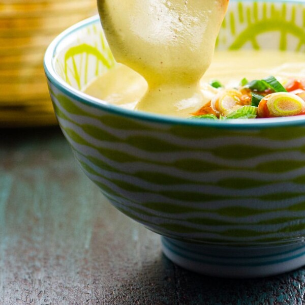 dipping into a bowl of vegan queso with tortilla chips