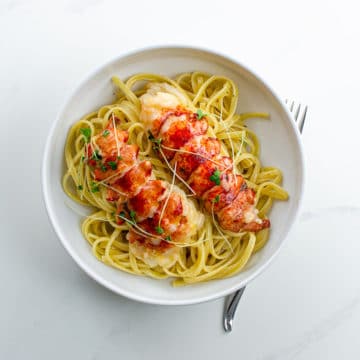 lobster poached in butter over linguine in a bowl