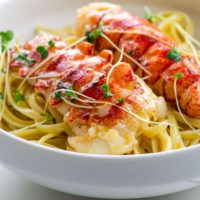butter poached lobster tails over linguine in a bowl