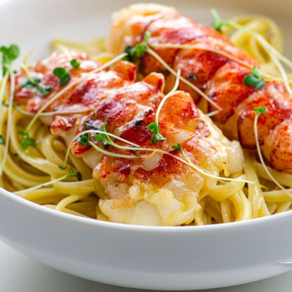 butter poached lobster tails over linguine in a bowl